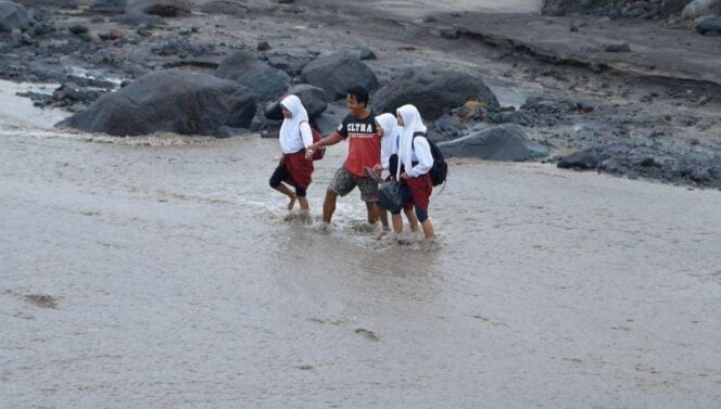 
					TEROBOS: Sejumlah siswa terpaksa menerobos aliran lahar hujan agar bisa bersekolah. (foto: Asmadi)