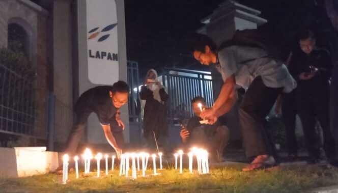 
					PRIHATIN: Fokalis Jatim saat menyalakan lilin di depan kantor BRIN Pasuruan. (foto: Moh. Rois).