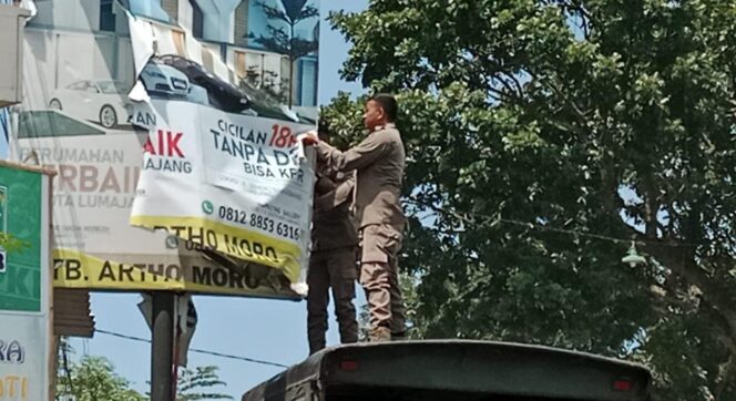 
					DITERTIBKAN: Petugas Satpol PP Lumajang saat menertibkan reklame yang tidak bayar pajak. (foto: Asmadi)