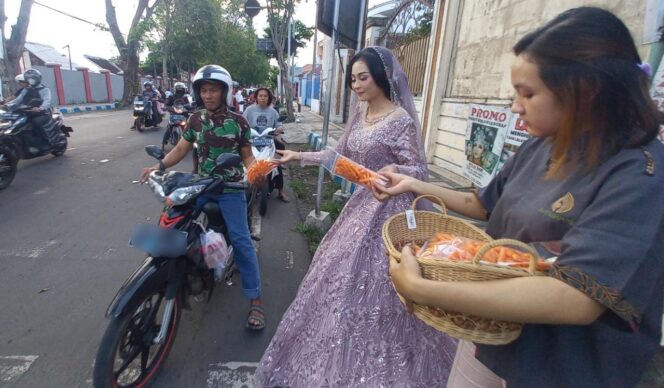 
					BERBAGI: Perempuan yang mengenakan baju pengantin sedang membagikan takjil di jalan raya Kota Pasuruan. (foto: Moh. Rois)