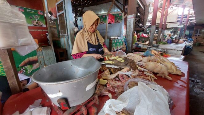 
					Juhariyah, pedagang daging ayam sedang memotong ayam.