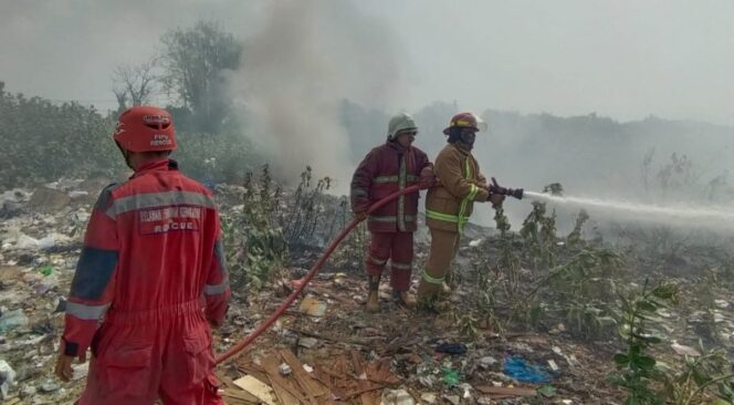 
					Petugas damkar memadamkan api yang membakar tumpukan sampah. (Foto: Istimewa)