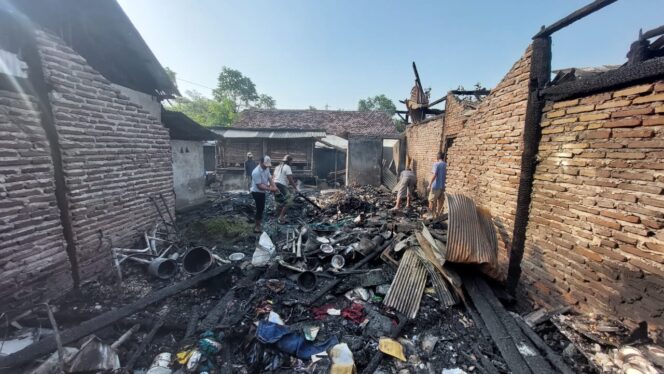 
					Warga sedang menyiram sisa puing rumah yang terbakar.