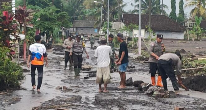 
					KOMPAK: Warga, relawan dan petugas gotong-royong membersihkan jalan yang tertutup lumpur. (foto: Asmadi)