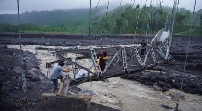 
					NEKAD: Warga melintasi Jembatan Kaliregoyo yang porak-poranda diterjang banjir bandang lahar hujan Gunung Semeru. (foto: Asmadi).