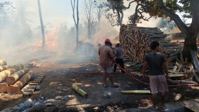 
					Petugas pemadaman kebakaran melakukan penyemprotan tumpukan kayu yang terbakar.