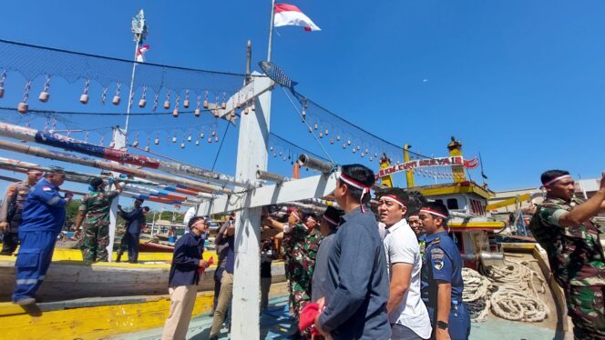 
					Dandim dan anggota Kodim 0820 mengganti bendera usang di kapal nelayan.