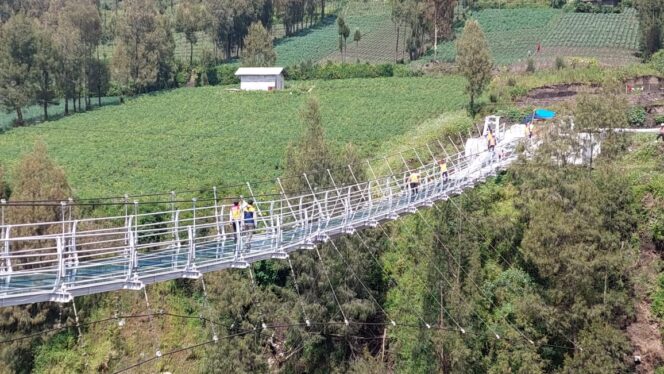 
					Sejumlah pekerja melintasi jembatan kaca di kawasan Gunung Bromo.