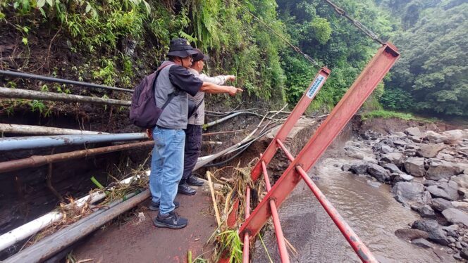 
					LONGSOR: Koordinator wisata Air Terjun Madakaripura dan anggota Polsek Lumbang, Kabupaten Probolinggo, menunjukkan lokasi putusnya akses jalan. (foto: Hafiz Rozani).