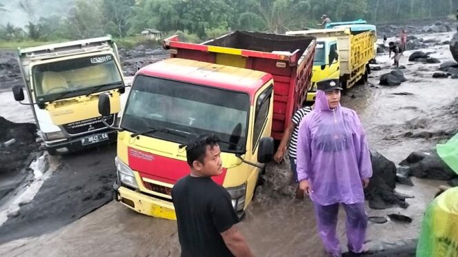 
					TERJEBAK: Deretan truk pasir yang terjebak aliran lahar Gunung Semeru. (foto: istimewa).