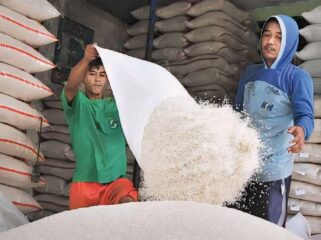 BERAS AMAN: Dua orang pekerja sedang mengemas ulang beras di dalam gudang. (foto: istimewa)
