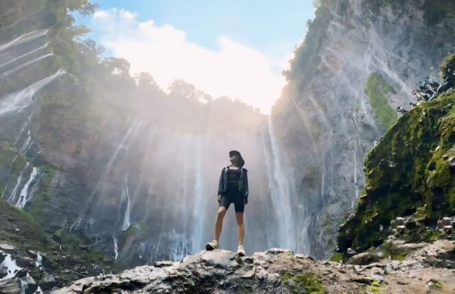 
					EKSOTIS: Seorang wisatawan tengah pose dengan latar belakang eksotika Air Terjual Tumpak Sewu Lumajang. (foto: istimewa).