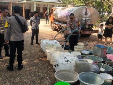 DROPING AIR : Anggota Polres Probolinggo Kota saat mengisi air ke jerigen milik warga Desa Sumberkramat, Kecamatan Tongas. (foto : istimewa)
