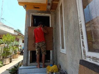 ANTISIPASI: Seorang tukang sedang memasang pembatas air di pintu rumah warga Desa/Kecamatan Dringu, Kabupaten Probolinggo. (foto: Hafiz Rozani)
