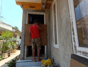 ANTISIPASI: Seorang tukang sedang memasang pembatas air di pintu rumah warga Desa/Kecamatan Dringu, Kabupaten Probolinggo. (foto: Hafiz Rozani)
