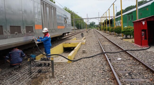 EFISIENSI: Petugas mengisi BBM ke lokomotif dan kereta pembangkit. (foto: Istimewa)
