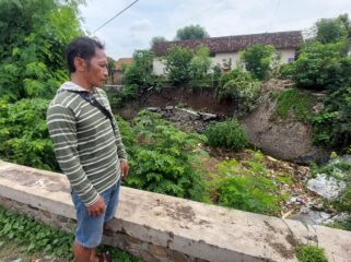 AMBROL: Slamet melihat plengsengan di aliran sungai Legundi Kota Probolinggo yang ambrol. (foto: Hafiz Rozani)
