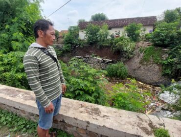 AMBROL: Slamet melihat plengsengan di aliran sungai Legundi Kota Probolinggo yang ambrol. (foto: Hafiz Rozani)
