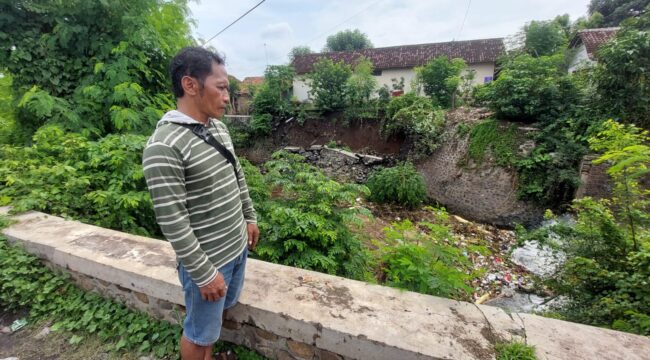 AMBROL: Slamet melihat plengsengan di aliran sungai Legundi Kota Probolinggo yang ambrol. (foto: Hafiz Rozani)
