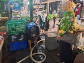 MENGGANGU: Petugas Disperindag Kab. Pasuruan saat mengecek dampak banjir di Pasar Bangil. (foto: Moh. Rois)