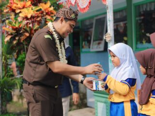 BERBAGI: Kejari Kabupaten Probolinggo, Ahmad Nuril Alam, saat memberikan MBG ke siswi SDN 1 Sebaung. (foto: Ali Ya'lu).