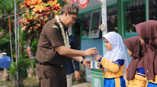 BERBAGI: Kejari Kabupaten Probolinggo, Ahmad Nuril Alam, saat memberikan MBG ke siswi SDN 1 Sebaung. (foto: Ali Ya'lu).