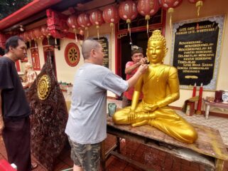 BERSIH-BERSIH: Pengurus klenteng Tri Dharma Sumber Naga Kota Probolinggo, Ervan Sudjuanto, sedang membersihkan patung Budha. (foto: Hafiz Rozani)
