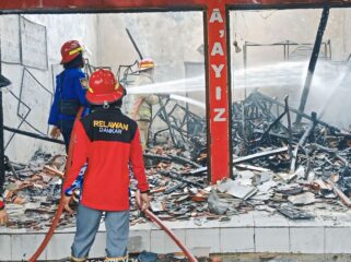 LUDES: Petugas Damkar Kabupaten Probolinggo sedang memadamkan api yang membakar ruko di  Desa Maron Kidul, Kecamatan Maron, Minggu (2/2/25) siang. (foto: Ali Ya'lu).