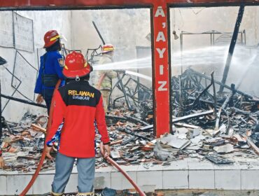 LUDES: Petugas Damkar Kabupaten Probolinggo sedang memadamkan api yang membakar ruko di  Desa Maron Kidul, Kecamatan Maron, Minggu (2/2/25) siang. (foto: Ali Ya'lu).