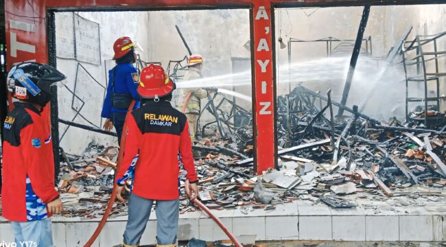 LUDES: Petugas Damkar Kabupaten Probolinggo sedang memadamkan api yang membakar ruko di  Desa Maron Kidul, Kecamatan Maron, Minggu (2/2/25) siang. (foto: Ali Ya'lu).