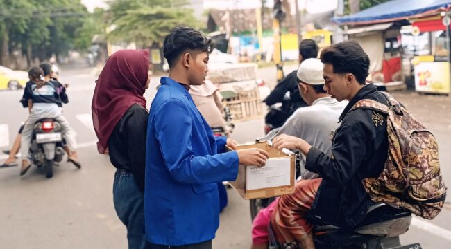 GALANG DANA: Seorang pengguna jalan memberikan bantuan kepada mahasiswa yang menggelar galang dana peduli bencana. (foto: Ali Ya'lu).
