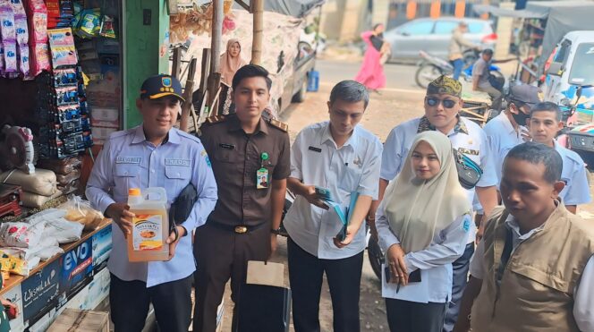 
					CURANG: Kepala DKUPP Taupik Alami (bertopi) menunjukkan kemasan 5 liter minyak goreng yang hanya berisi 3,5 liter. (foto: Ali Ya'lu).
